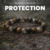 Bracelet premium aux perles noires, grises et brun doré posé sur des rochers de sous-bois, avec titre Protection